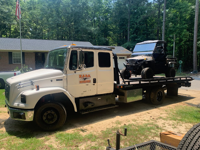 A tow truck with a boat on the back of it